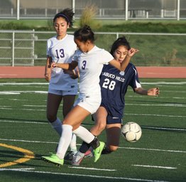 Three girls kicking a soccer ball